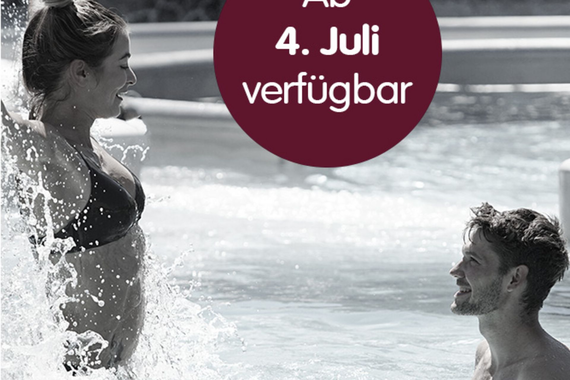 Ein Paar amüsiert sich im Wasser eines Wellnessbads, während die Frau lachend Wasser aufspritzt. Im Zentrum ein runder, weinroter Button mit der Aufschrift „Ab 4. Juli verfügbar“.